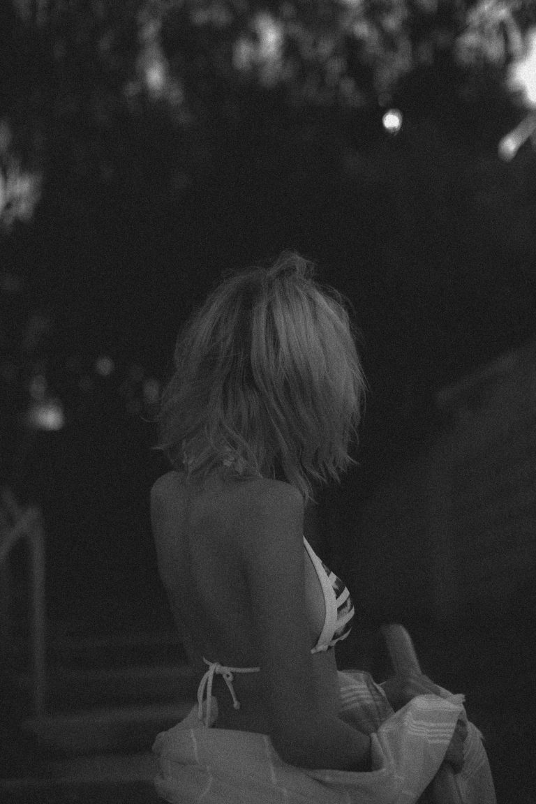 Back view of a woman in a bikini looking off, symbolizing quiet longing and the tension of playing small
