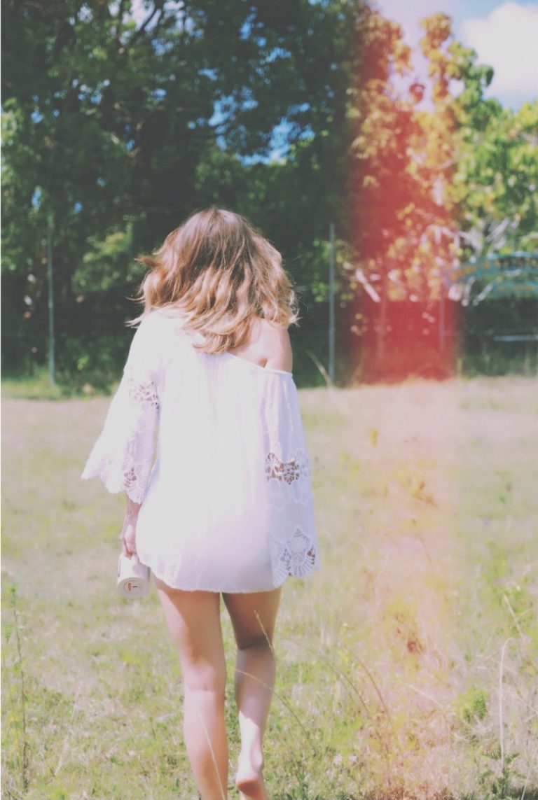 Empowered woman with arms outstretched running freely through an open field, symbolizing stepping into your power and embracing authentic self-confidence
