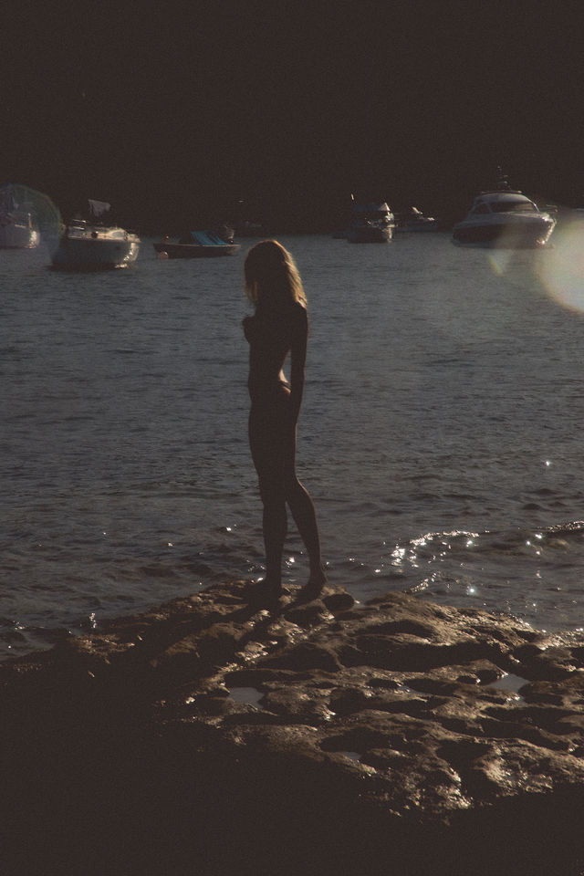 Confident woman standing on rocks in summer, embracing freedom and self-expression, symbolizing women empowerment and Becoming Her.