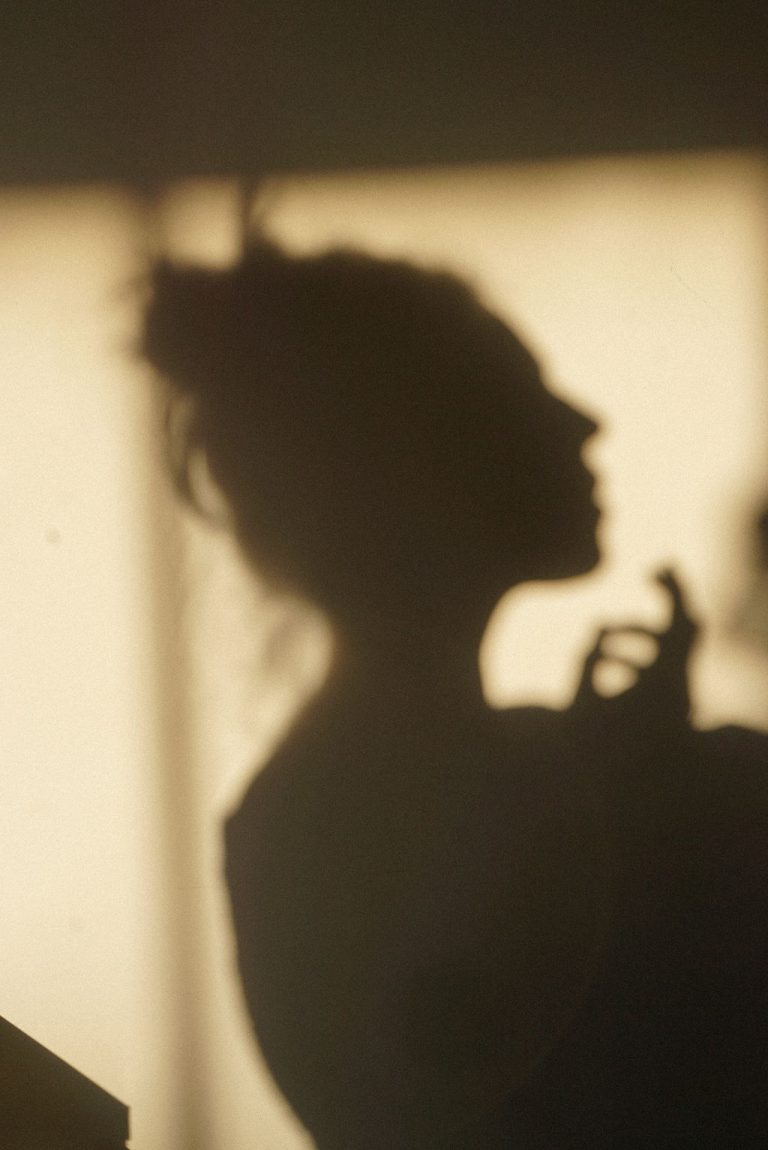 silhouette of a woman standing confidently against a wall, symbolizing empowerment and self-devotion
